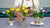 Instructor displaying spring clay flower arrangements with yellow and purple crocuses, white snowdrops, green leaves, and exposed bulbs.
