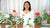Instructor displaying potted clay geraniums with red, pink, and white flowers, green frog figurines, and small ladybugs.