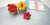 Red and yellow clay hibiscus flowers in woven containers beside DECO Flower Course 1 and Tropical Course 1 books.
