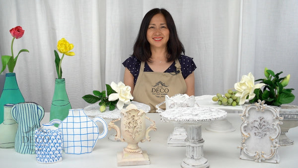 Instructor displaying handcrafted clay compote, flat, and tall vases in white, cream, turquoise, and blue-patterned designs.