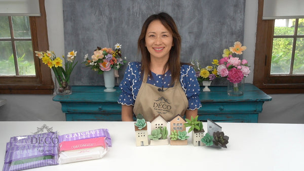 Instructor behind miniature house-shaped planters filled with handcrafted green clay succulents.