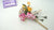 New Year clay arrangement with pink Phalaenopsis orchids, yellow Dendrobium orchids, a white snake zodiac figure, and decorative foliage.